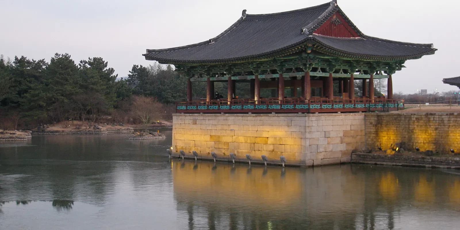 밤 조명이 켜진 경주 동궁과 월지의 복원 전각과 연못 수면에 비친 반영