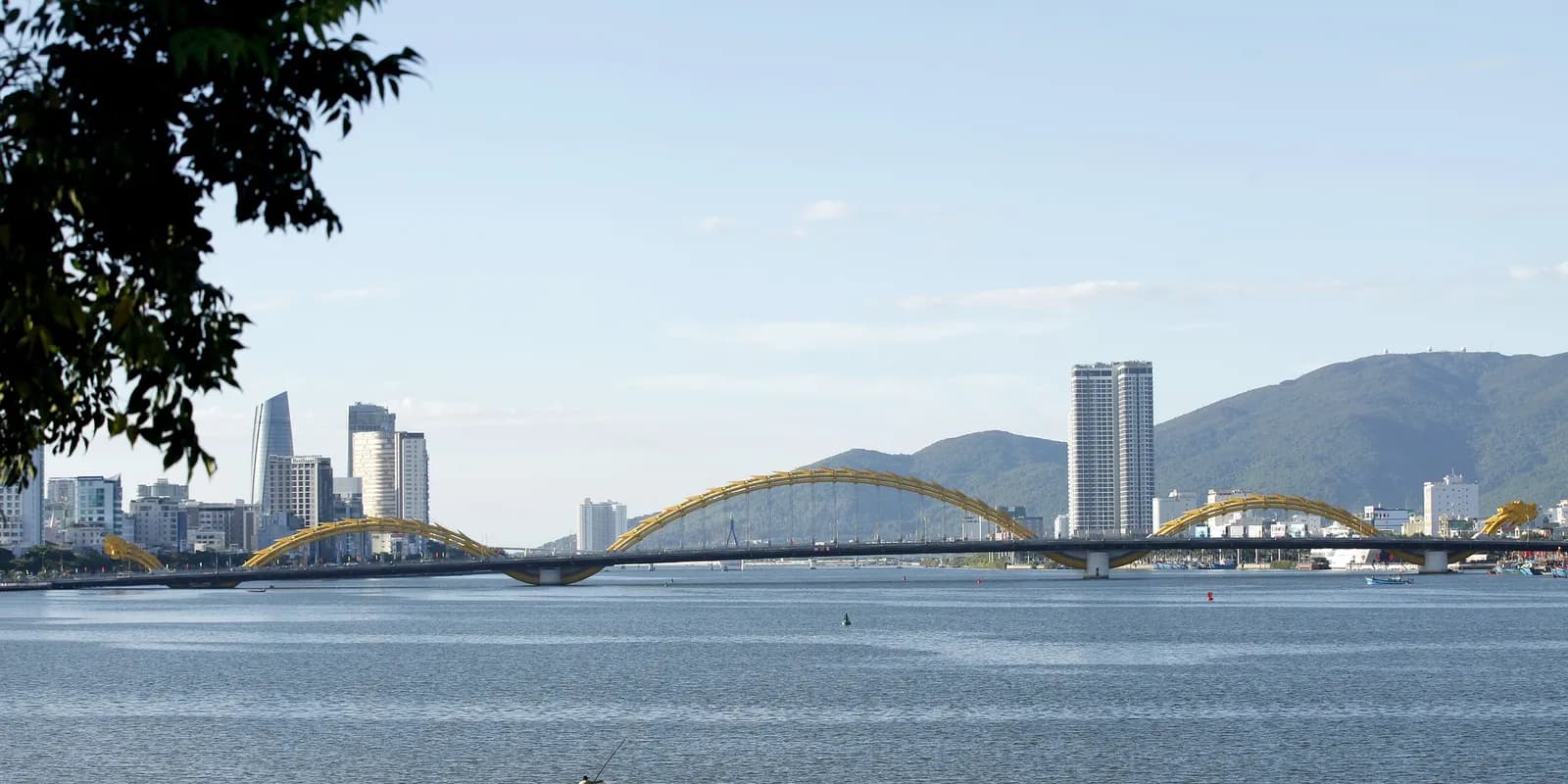 밤에 노란 조명이 켜진 다낭 용다리(Dragon Bridge)가 한강 위로 용 모양으로 이어진 모습