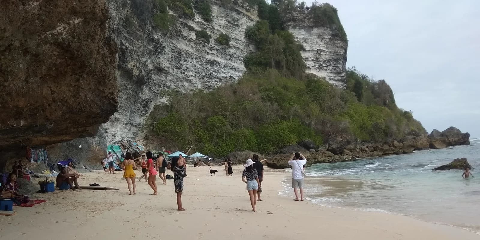 발리 울루와뚜 술루반 해변의 석회암 절벽과 모래사장, 바위 사이로 드나드는 사람들