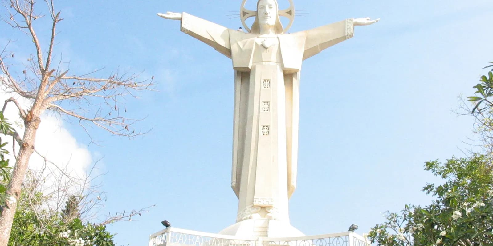 붕따우 작은 산 정상에 두 팔을 펼치고 서 있는 예수상과 그 아래로 펼쳐진 해안 도시 전경